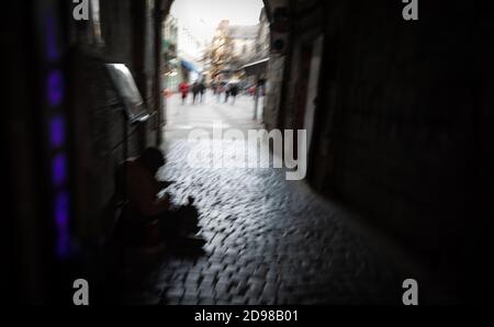 Obdachloser. Verschwommenes Bild eines Bettlers, der auf der Straße sitzt und auf Almosen wartet. Stockfoto