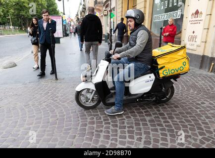 Lviv, Ukraine - 25. Mai 2020: Ein Glovo-Kurier liefert Lebensmittel in Lviv, Ukraine. Stockfoto