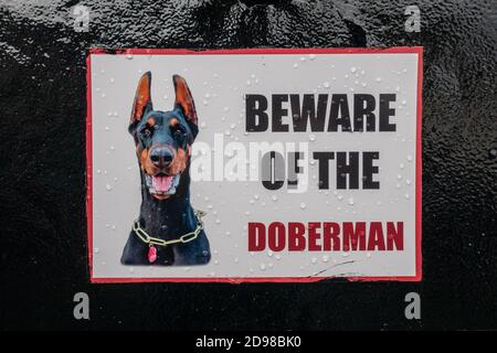 Vorsicht vor dem Hundeschild an einem Tor mit Dobermann Stockfoto