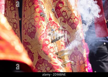 Ein Rauchfass in der Hand eines orthodoxen christlichen Priesters in einer bestickten Kirchenkassie. Stockfoto