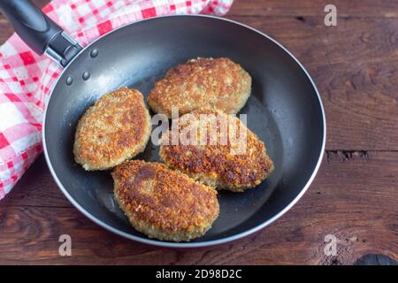 Saftig leckeres Hähnchen oder Putenschnitzel in einer Pfanne auf einem dunklen Holztisch. Rustikaler Stil. Selektiver Fokus, Draufsicht. Stockfoto