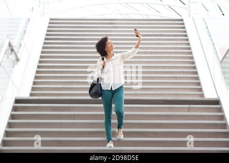 Portrait einer glücklichen Frau, die ein Selfie über die Treppe macht Stockfoto