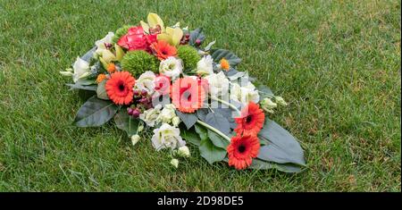 Längliche Blumenarrangements für Allerheiligen. Grabstück auf dem Gras. Stockfoto