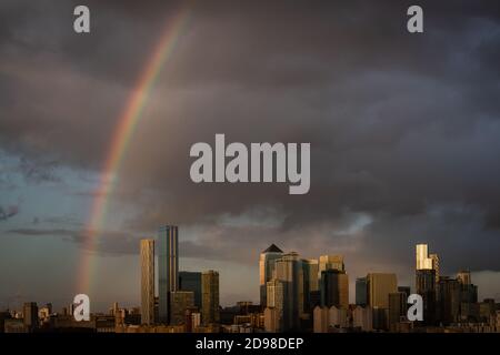 London, Großbritannien. November 2020. UK Wetter: Ein massiver Regenbogen bricht über East London und Canary Wharf Business Park Gebäude nach einem kurzen Sonnenuntergang Regensturm. Kredit: Guy Corbishley/Alamy Live Nachrichten Stockfoto