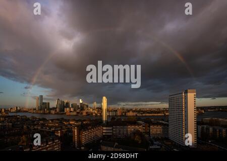 London, Großbritannien. November 2020. UK Wetter: Ein massiver Regenbogen bricht über East London und Canary Wharf Business Park Gebäude nach einem kurzen Sonnenuntergang Regensturm. Kredit: Guy Corbishley/Alamy Live Nachrichten Stockfoto