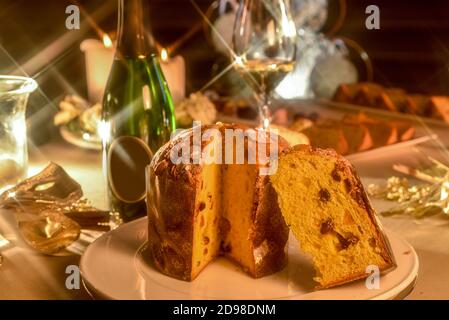 Panettone auf dem Tisch im Weihnachtsstil, in der verschwommenen Hintergrund Flasche und Glas Champagner und Kerzen Stockfoto