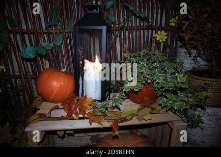 Street Halloween Deko mit Kürbissen, Blumentöpfen, Landzaun und großer Kerze Stockfoto