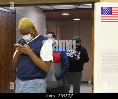 Racine, Wisconsin, USA. November 2020. Die Wähler schauen sich ihre Telefone an, während sie am Wahltag am 2. November 2020 im Dr. John Bryant Community Center, einem Wahllokal in Racine, Wisconsin, Schlange stehen. (Bild: © Mark HertzbergZUMA Wire) Stockfoto