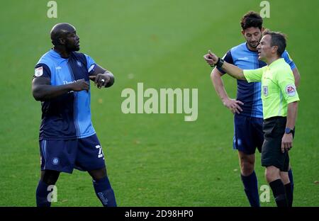 Adebayo Akinfenwa von Wycombe Wanderers (links) spricht mit dem Schiedsrichter während des Sky Bet Championship-Spiels im Adams Park, London. Stockfoto