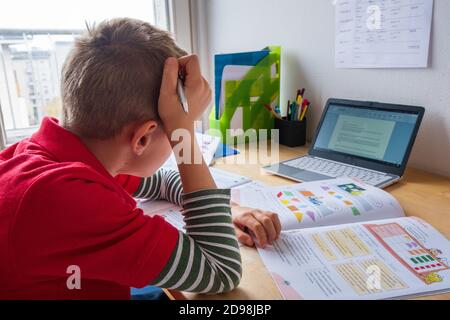 Junge, der sich beim Heimatschooling während der Corona Lockdown gelangweilt sah Stockfoto