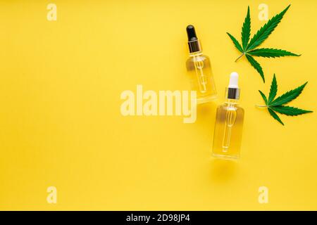 Hanföl-Serum in Glastropfer mit Cannabisblatt. Cannabisblätter mit kosmetischen Produkten CBD-Öl auf gelbem Hintergrund mit Kopierraum Stockfoto