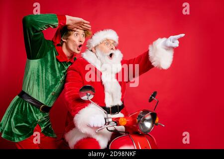 Profilfoto von zwei Personen Elf santa Motorrad direkten Finger Suchen Sie leeren Raum tragen x-Mas Kostüm Mantel Kappe isoliert rot Farbiger Hintergrund Stockfoto