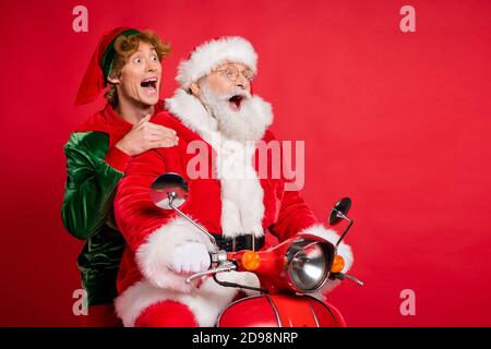 Profilfoto von Elf santa Ride Moped offenen Mund Blick Leerer Raum Tragen x-Mas Kostüm Mantel Kappe isoliert rote Farbe Hintergrund Stockfoto