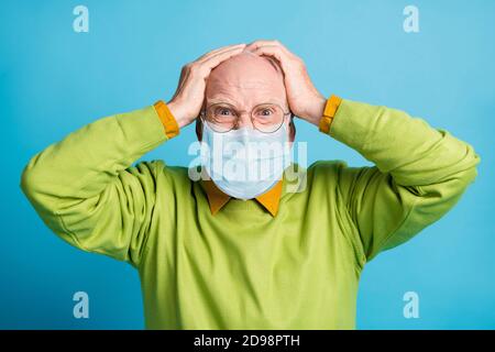 Foto von aggressiven alten Mann Hände Kopf verrückt Look tragen Blaue Gesichtsmaske isoliert blauen Hintergrund Stockfoto