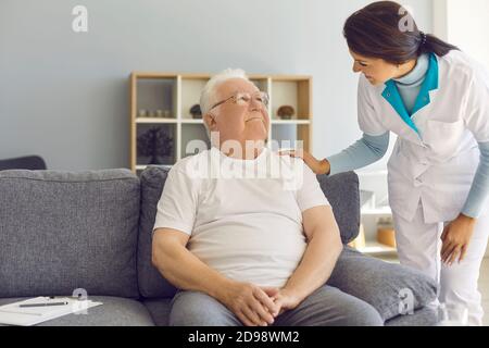 Freundlicher Arzt oder hilfsbereite Krankenschwester kommt zum Seniorpatienten Zu Hause oder in betreuten Wohnanlagen Stockfoto