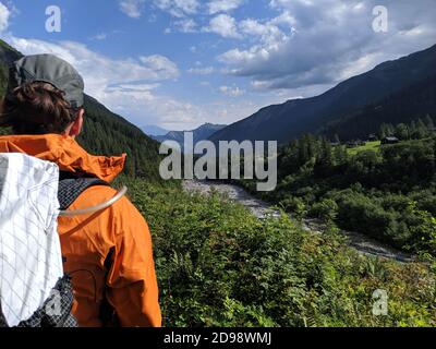 Frau Wanderer bewundern die Aussicht auf die Alpen während der berühmten Trekking-Kurs der Tour du Mont Blanc. Blick auf den Fluss, umgeben von Wäldern in den Alpen. O Stockfoto