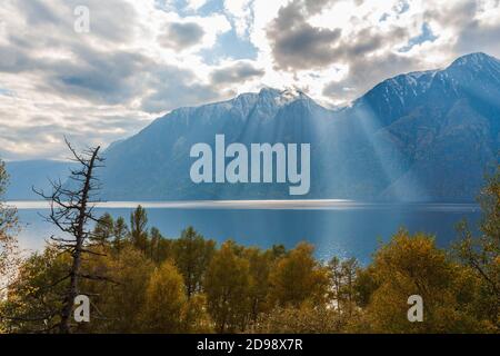 Die Herbstsonne, die durch die Wolken bricht, erhellt den erstaunlich schönen See Teletskoye in den Bergen, Altai-Gebirge. Stockfoto