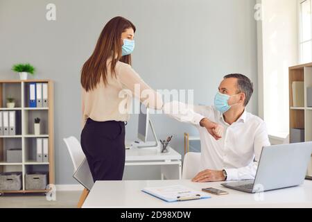 Zwei Geschäftsleute im Gesicht decken Masken stoßen Ellbogen als Eine Alternative zum Handshake Stockfoto