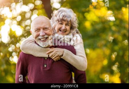 Glückliches Seniorenpaar, das Zeit zusammen in einem wunderschönen Stadtpark verbringt Im Herbst Stockfoto