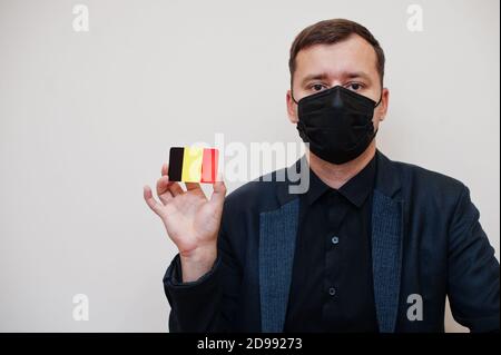 Europäischer Mann tragen schwarz formell und schützen Gesichtsmaske, halten Belgien Flagge Karte isoliert auf weißem Hintergrund. Europa Coronavirus Covid Länderkonzept. Stockfoto