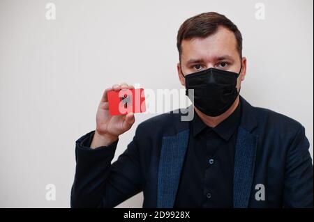 Europäische Mann tragen schwarz formell und schützen Gesichtsmaske, halten Albanien Flagge Karte isoliert auf weißem Hintergrund. Europa Coronavirus Covid Länderkonzept. Stockfoto