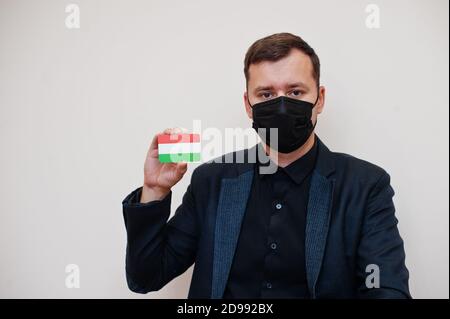 Europäische Mann tragen schwarz formell und schützen Gesichtsmaske, halten Ungarn Flagge Karte isoliert auf weißem Hintergrund. Europa Coronavirus Covid Länderkonzept. Stockfoto