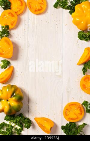 Gelbe Tomaten mit Paprika und Sesam auf weißem Holzhintergrund, Draufsicht Stockfoto