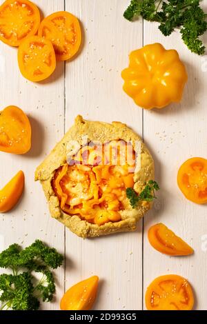 Torte mit gelben Tomaten, Paprika und Sesam, Galette mit Gemüse und Käse auf weißem Holzhintergrund, Draufsicht Stockfoto