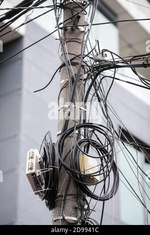 Viele unorganisierte Internet- und TV-Kabel an einem Betonmast in Bukarest. Stockfoto