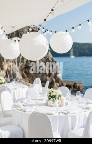 Gedeckte Tische für eine weiße Party auf einem Hintergrund Das Meer Stockfoto