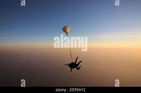 Skydiving Tandem bei dem atemberaubenden Sonnenuntergang Stockfoto