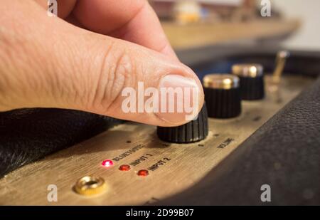 Finger passt die Feinabstimmung der Regler des Retro-Bluetooth-Lautsprechers an. Selektiver Fokus Stockfoto