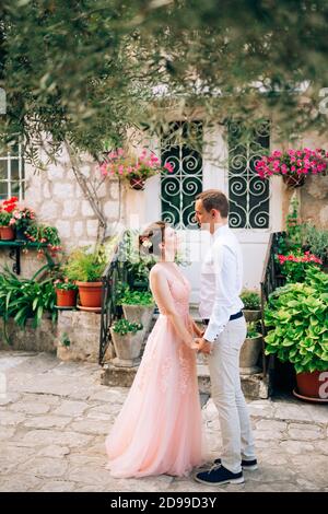 Braut und Bräutigam schauen einander an und halten die Hände fest In Perast Stockfoto