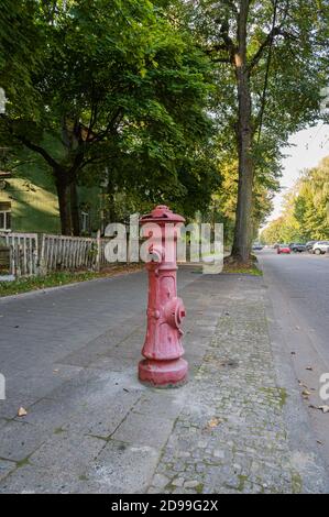 Alter roter Metallhydrant auf einer verlassenen Straße, Nahaufnahme, vertikale Ansicht Stockfoto