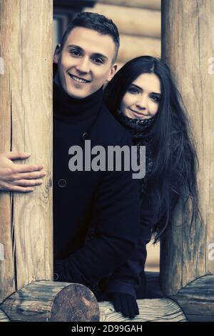 Glückliche junge Mode Paar auf der Veranda der Hütte stilvoll trendy Mann und Frau Tragen klassische Mantel Stockfoto