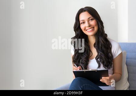 Porträt einer jungen Frau im Büro. Frau schreibt Daten in den Fragebogen Stockfoto