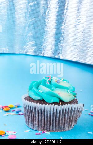 Frische hausgemachte Schokolade Cupcake mit bunten Dekoration dekoriert, leckere und lustige Muffin mit bunten Süßigkeiten auf blauem Hintergrund, Urlaub oder p Stockfoto