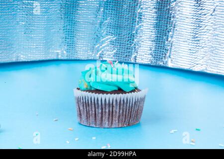 Frische hausgemachte Schokolade Cupcake mit bunten Dekoration dekoriert, leckere und lustige Muffin mit bunten Süßigkeiten auf blauem Hintergrund, Urlaub oder p Stockfoto