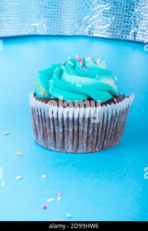 Frische hausgemachte Schokolade Cupcake mit bunten Dekoration dekoriert, leckere und lustige Muffin mit bunten Süßigkeiten auf blauem Hintergrund, Urlaub oder p Stockfoto