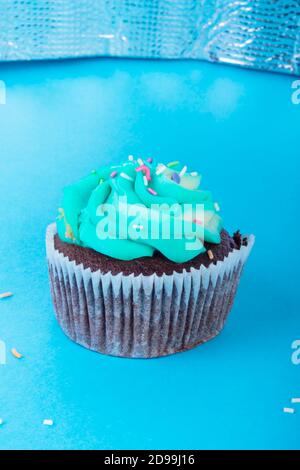 Frische hausgemachte Schokolade Cupcake mit bunten Dekoration dekoriert, leckere und lustige Muffin mit bunten Süßigkeiten auf blauem Hintergrund, Urlaub oder p Stockfoto