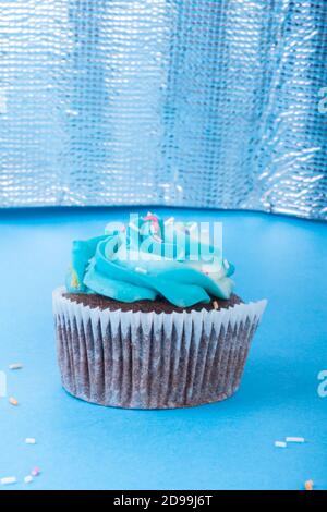 Frische hausgemachte Schokolade Cupcake mit bunten Dekoration dekoriert, leckere und lustige Muffin mit bunten Süßigkeiten auf blauem Hintergrund, Urlaub oder p Stockfoto