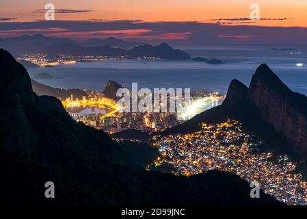 Blick auf Favela Rocinha bei Nacht mit dem Ipanema Distrikt dahinter, in Rio de Janeiro, Brasilien Stockfoto