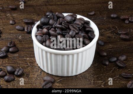 Geröstete Kaffeebohnen in weißer Schüssel. Rustikaler Hintergrund Stockfoto