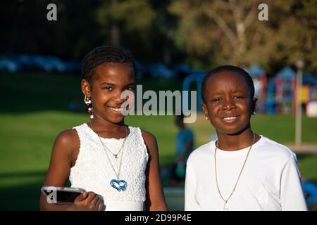 Ein Porträt von zwei afroamerikanischen Kindern, 8-10 Jahre alt, alle in weiß gekleidet. Wir sind gerade von einer Hochzeit im Park zurückgekommen. Brea, CA, USA Stockfoto
