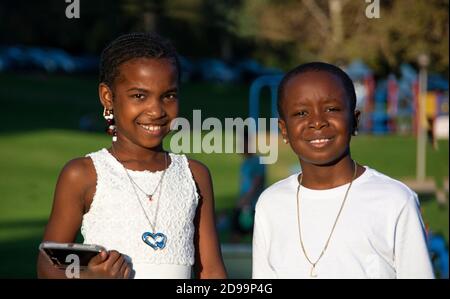 Ein Porträt von zwei afroamerikanischen Kindern, 8-10 Jahre alt, alle in weiß gekleidet. Wir sind gerade von einer Hochzeit im Park zurückgekommen. Brea, CA, USA Stockfoto