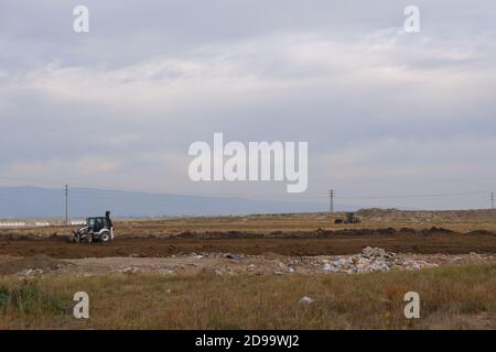 Planierraupen und LKWs arbeiten auf dem Feld bei bewölktem Wetter Stockfoto