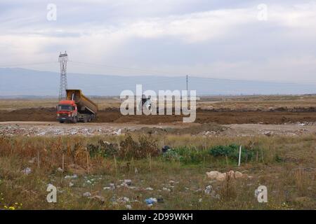 Planierraupen und LKWs arbeiten auf dem Feld bei bewölktem Wetter Stockfoto