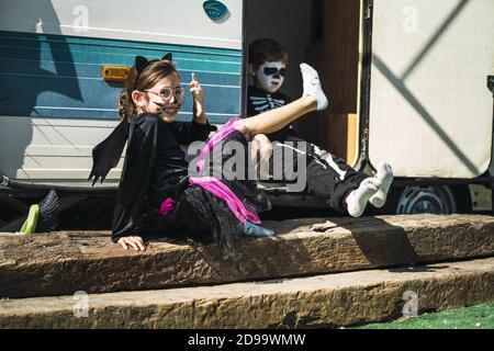 Schwester und Bruder tragen Halloween Kostüme und sitzen davor Eines Wohnwagens Stockfoto