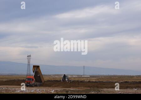 Planierraupen und LKWs arbeiten auf dem Feld bei bewölktem Wetter Stockfoto