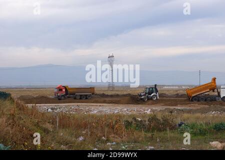 Planierraupen und LKWs arbeiten auf dem Feld bei bewölktem Wetter Stockfoto